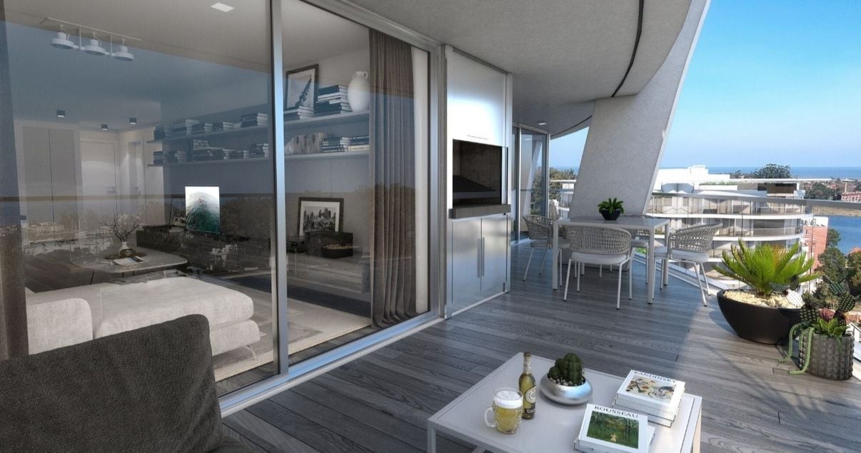 Amplio balcón con mesa y sillas de un moderno apartamento en el edificio AVA La Caleta de Compass desarrollo inmobiliario